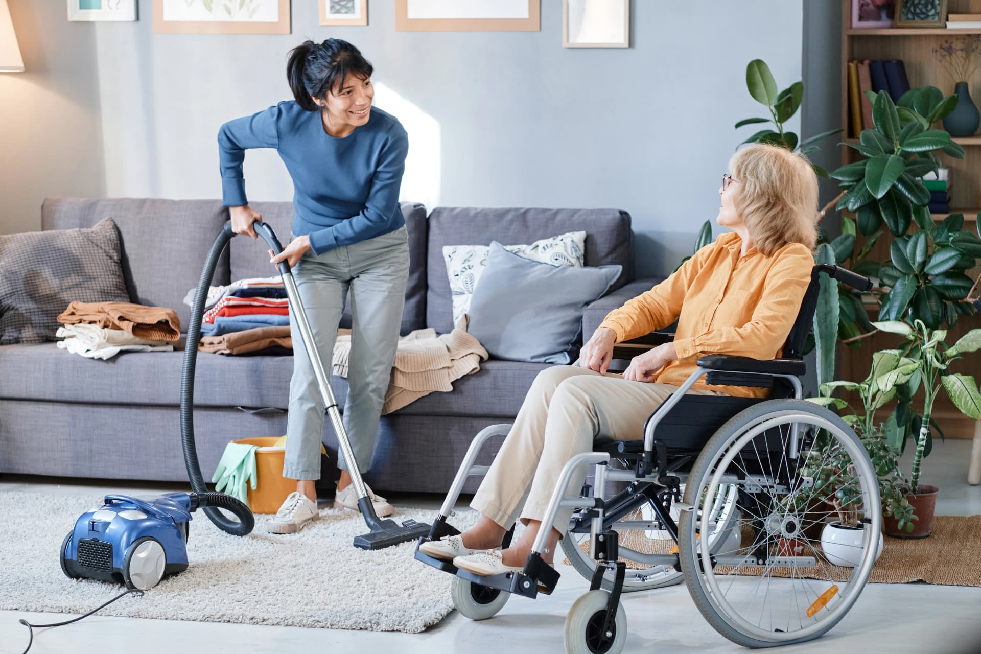 Woman vacuuming with friend in wheelchair